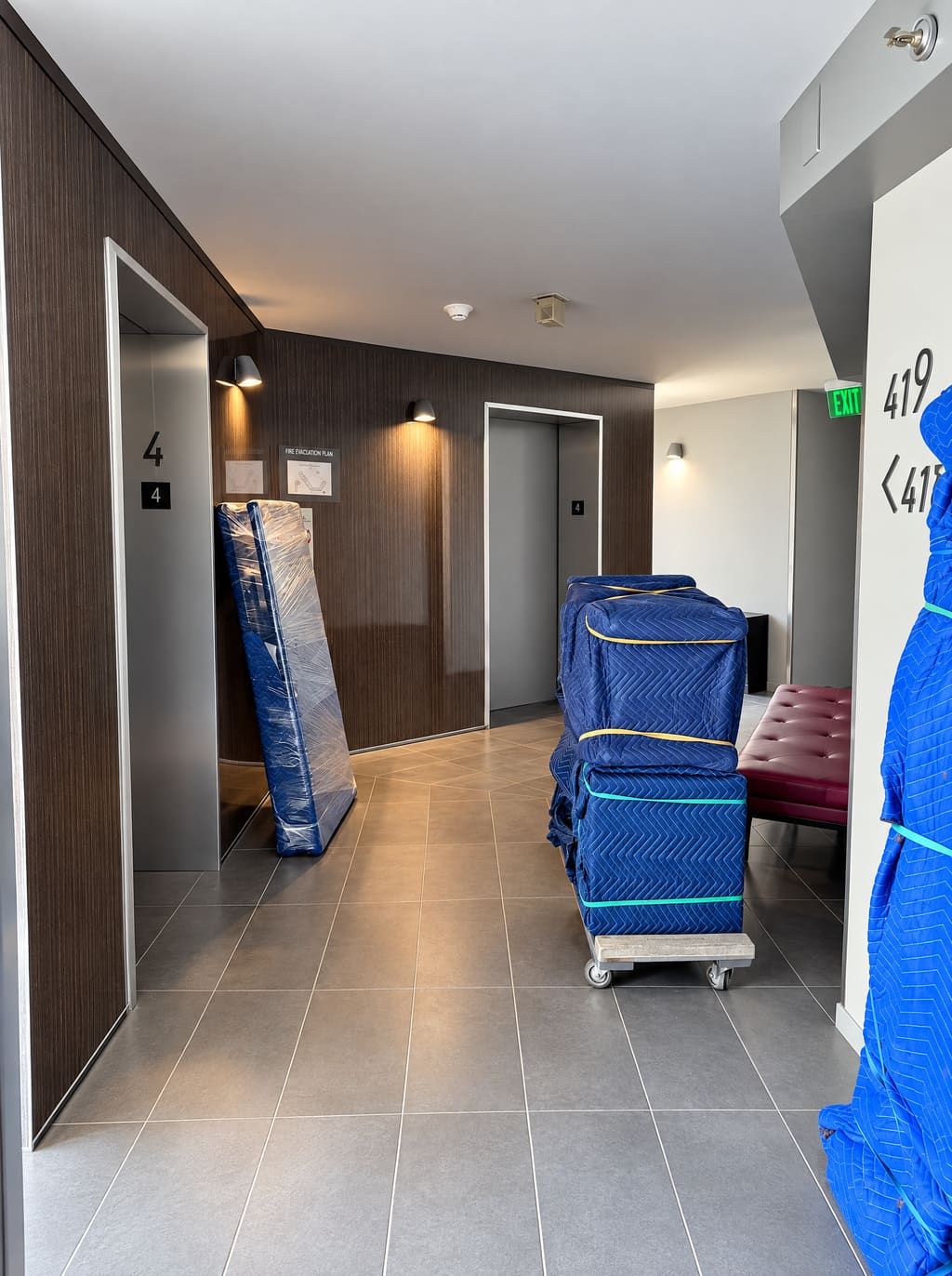Condo hallway with wrapped furniture on carts by the elevator