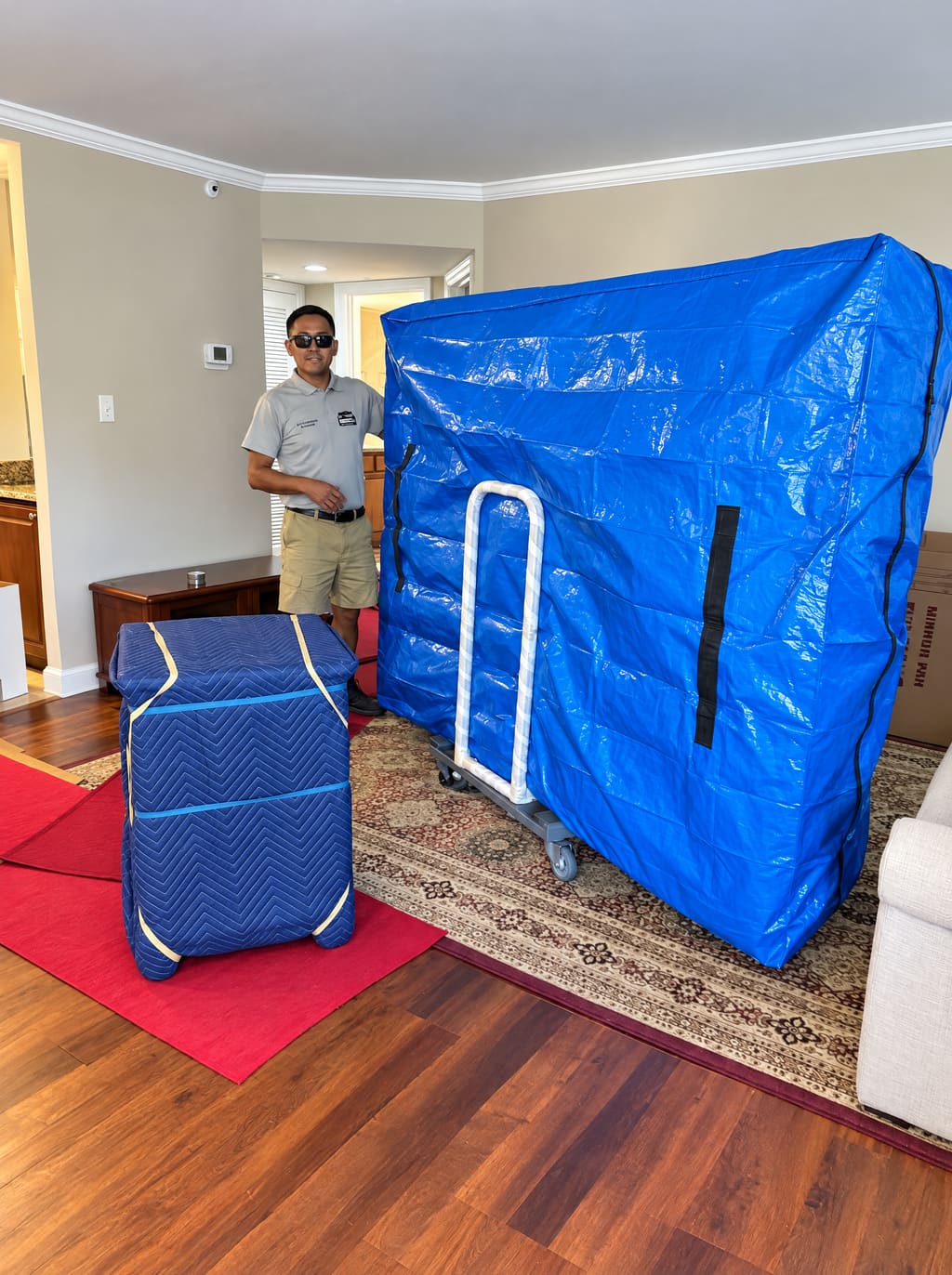 A Brunalli mover in a living room with a wardrobe in a blue cover on a dolly