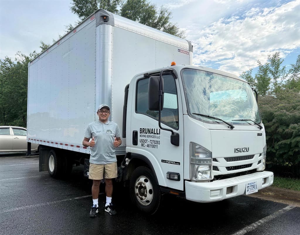 Luis giving a thumbs up in front of the white Brunalli Moving Services box truck
