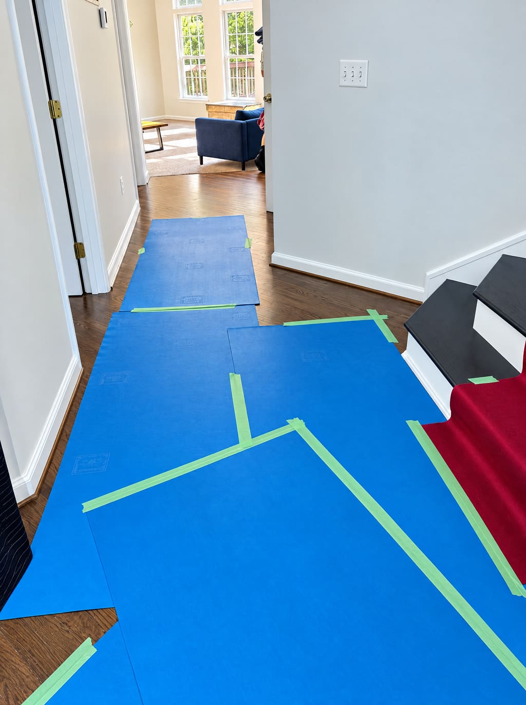 Blue floor protection taped across a foyer up to the stairs