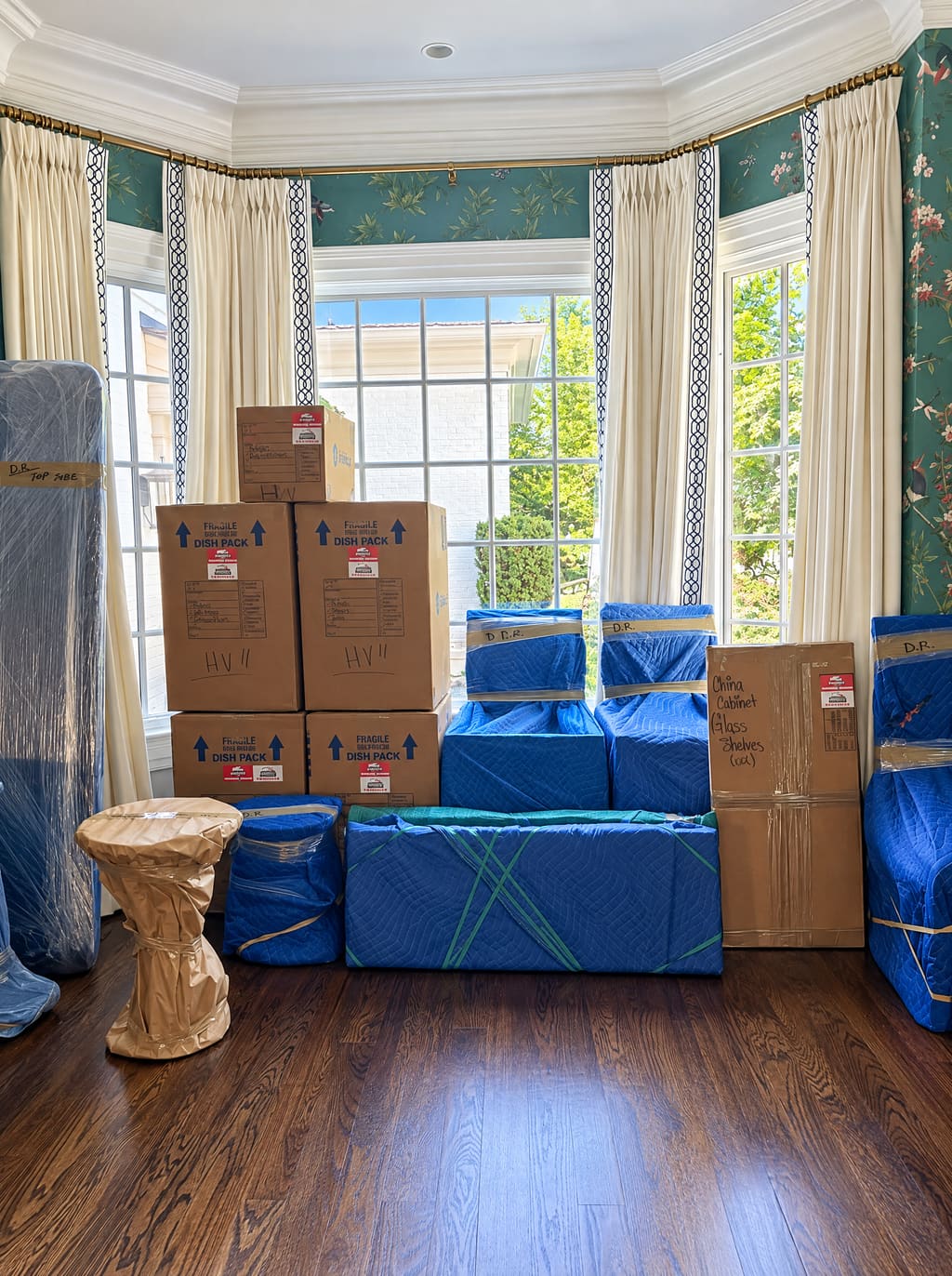Packed boxes and wrapped furniture staged by a bay window