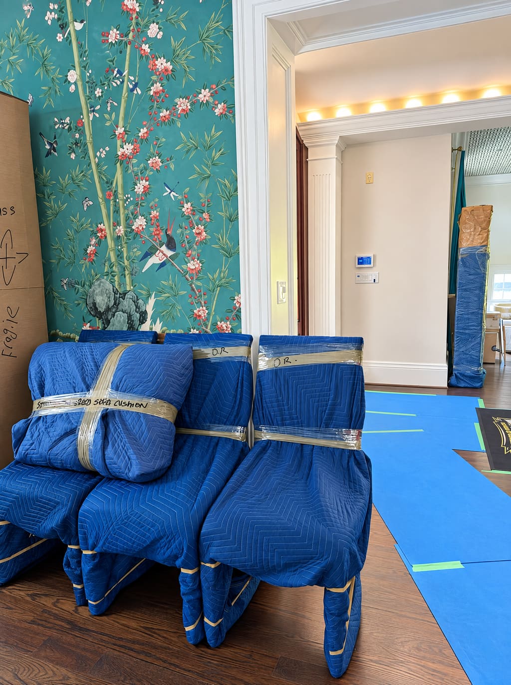 Dining chairs wrapped in blue moving blankets